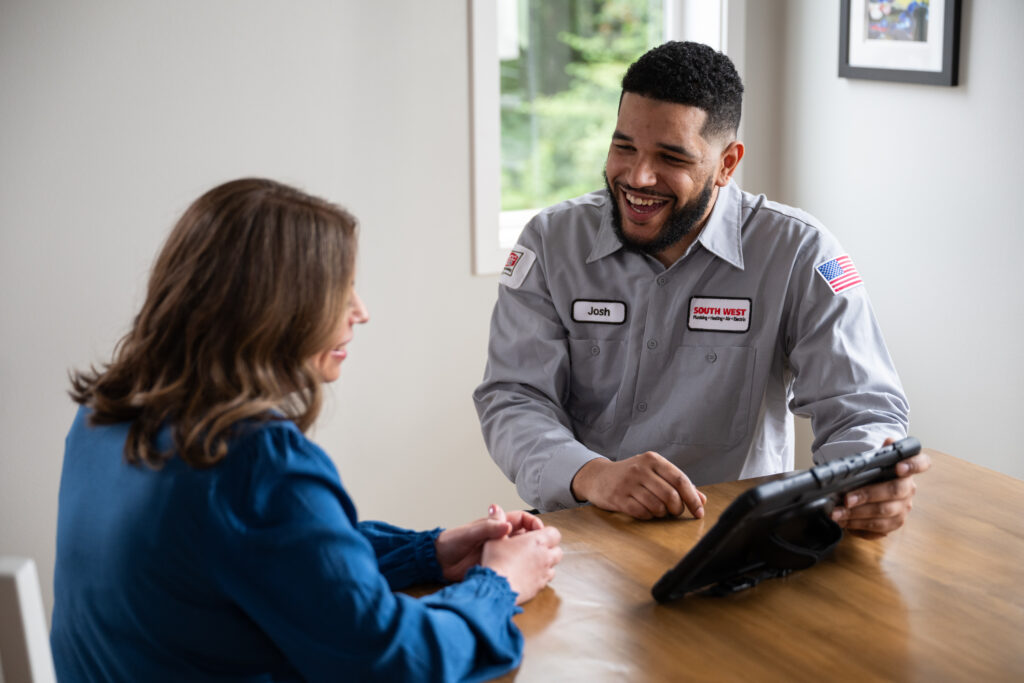 Plumber talking to customer at a dining table.