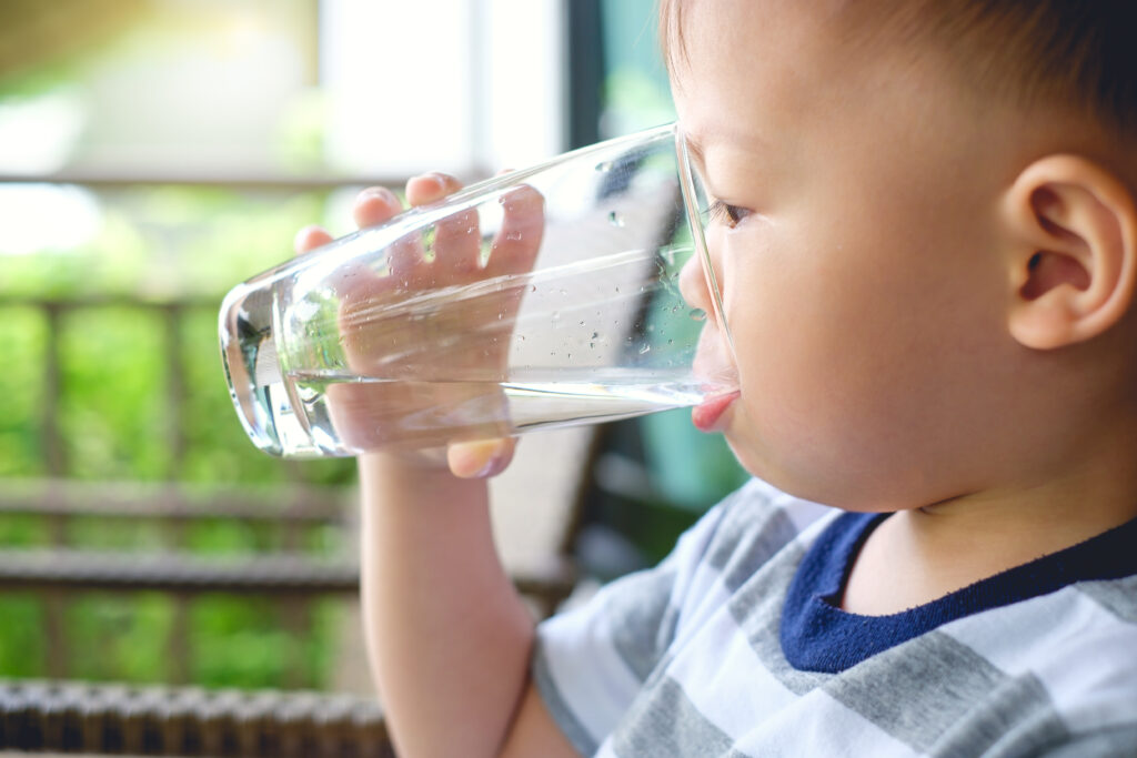 Toddler drinking a glass of filtered tap water